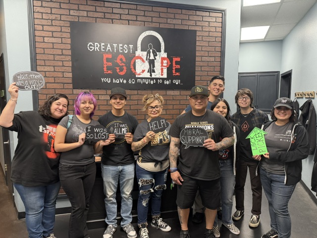 Group celebrating beneath the Greatest Escape sign