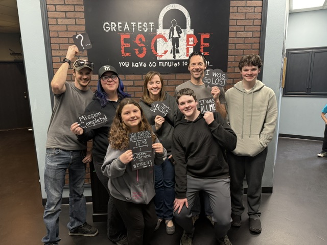 Group celebrating beneath the Greatest Escape sign